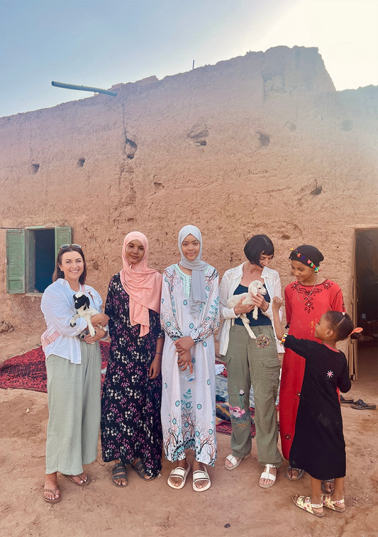 Women in M'Hamid stand in front of family home with two baby goats