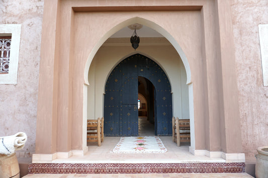Moroccan rug under an arched entryway with ornate dark blue arched door