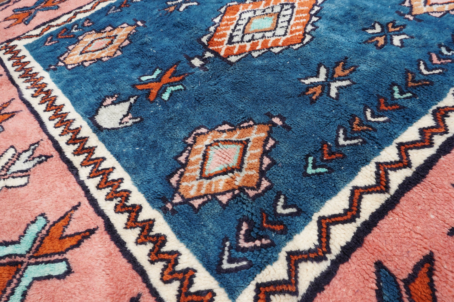 Close-up of a patterned rug with blue, pink, and white colors.