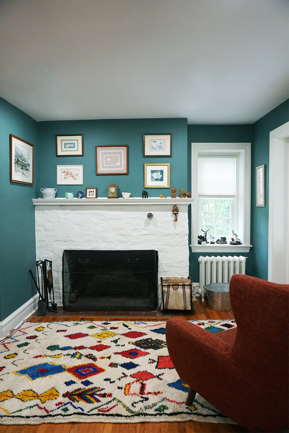 Living room with teal walls, white fireplace, and colorful rug.