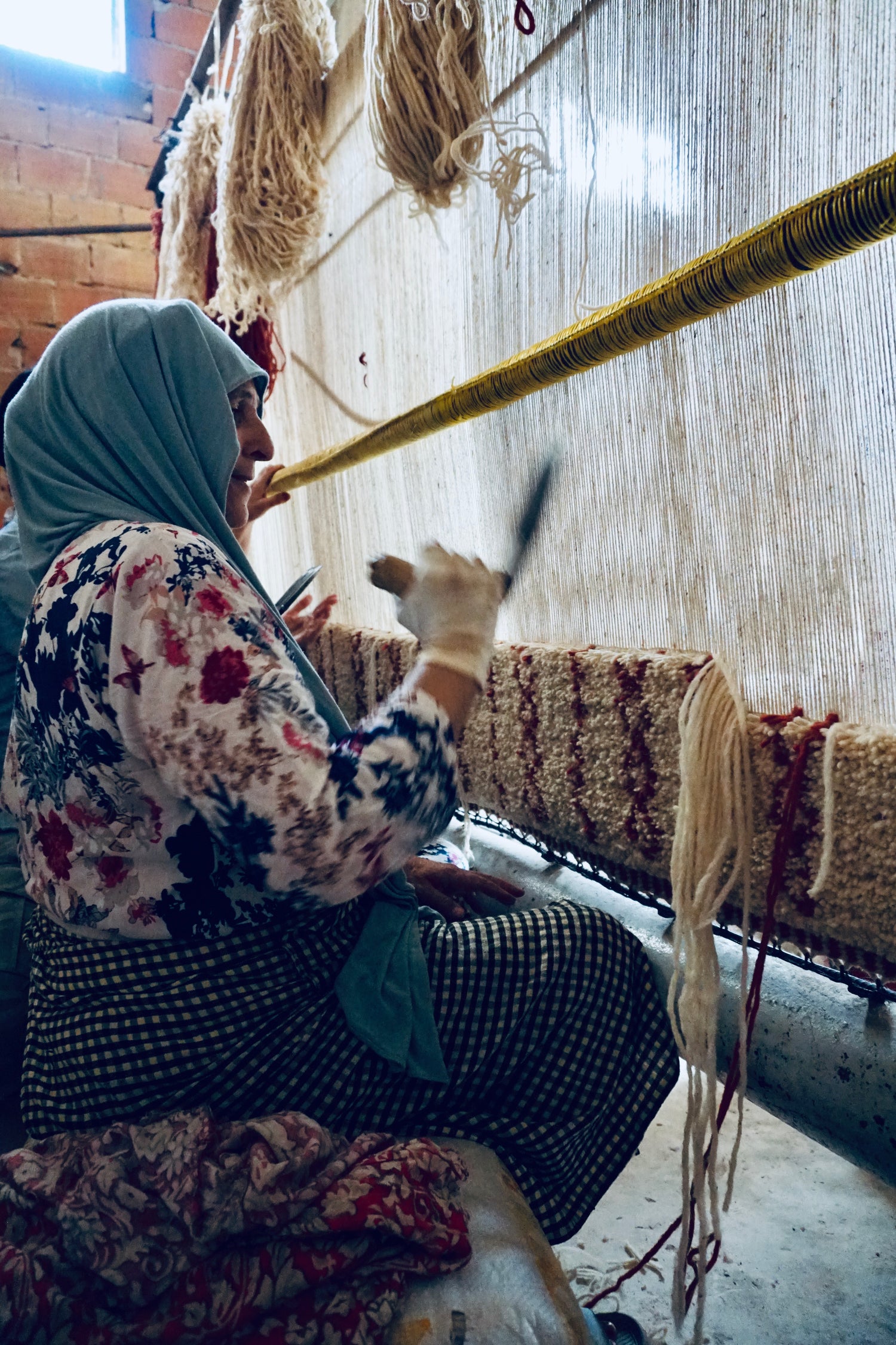 Moroccan artisan hand weaving white and red wool rug on loom