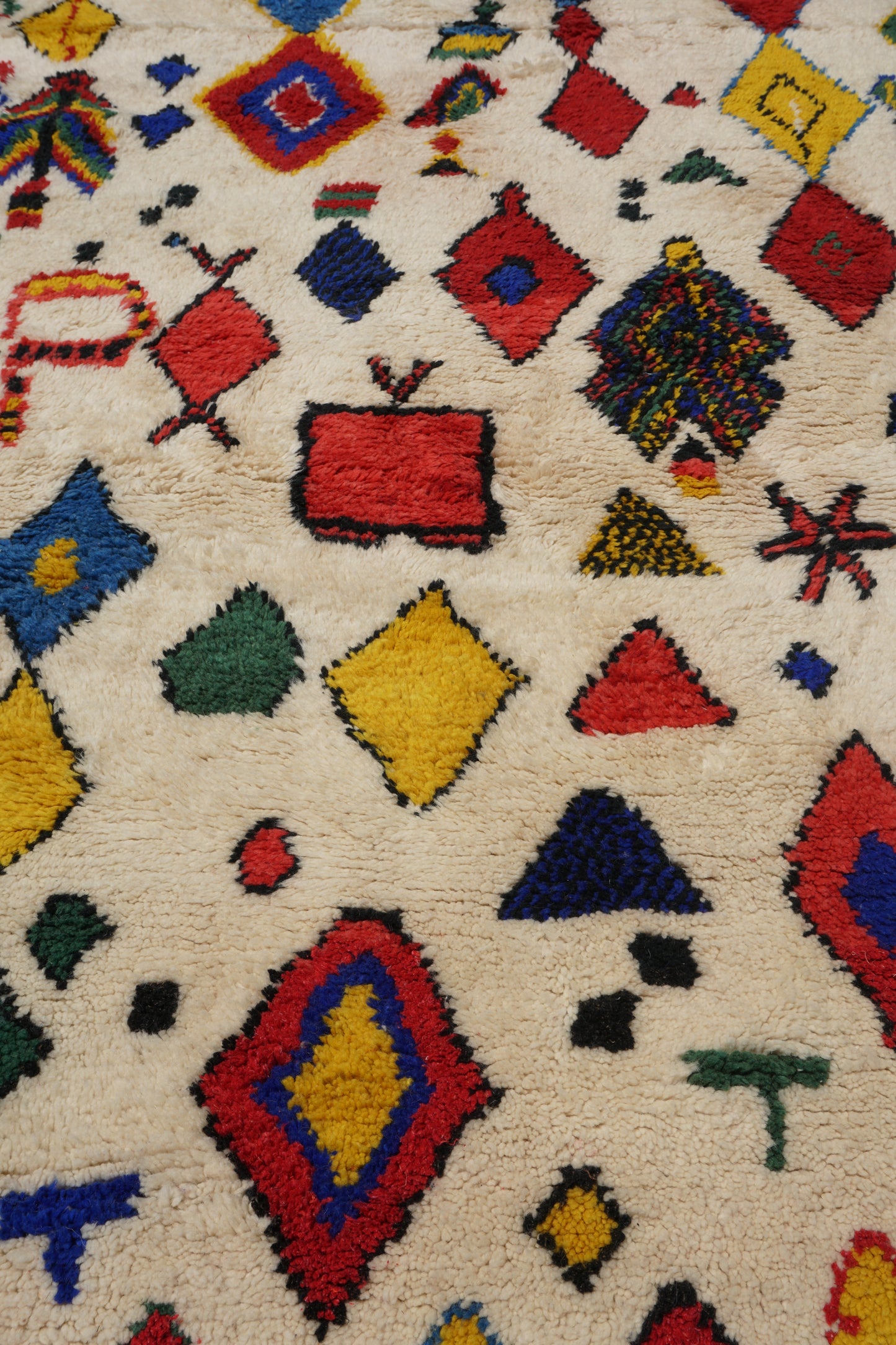 Colorful geometric patterned rug with various shapes and colors on a beige background